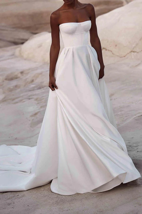 Un abito da sposa in raso bianco con strascico a palazzo e senza spalline